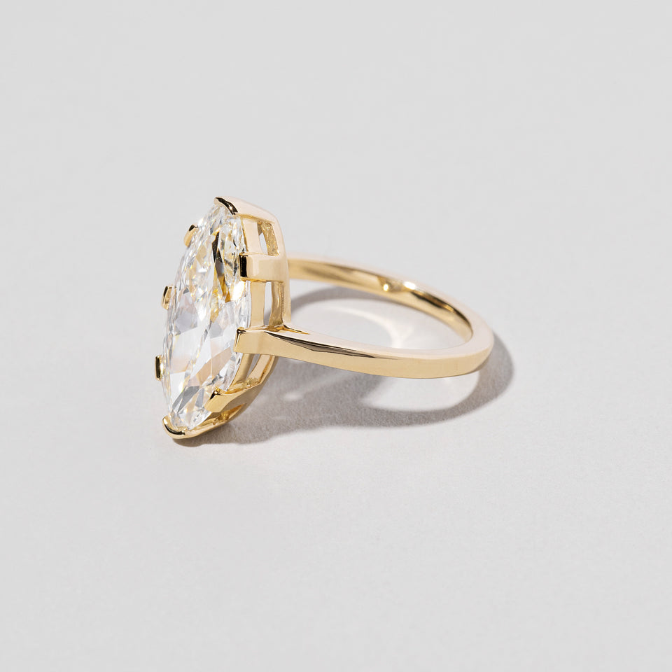 product_details::Closeup details of the North-South Navette Diamond Solitaire Ring on light color background.