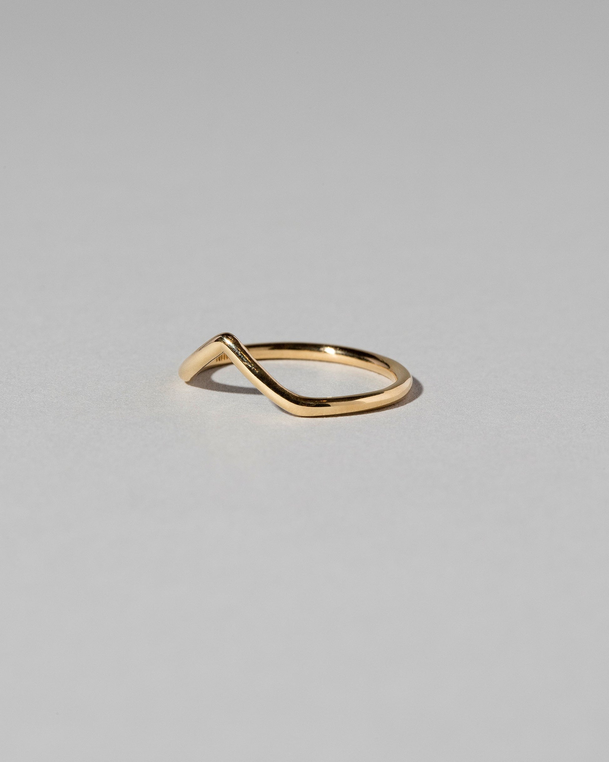 View from the side of the Gold Solid Round Wire High Peak Band on light color background.