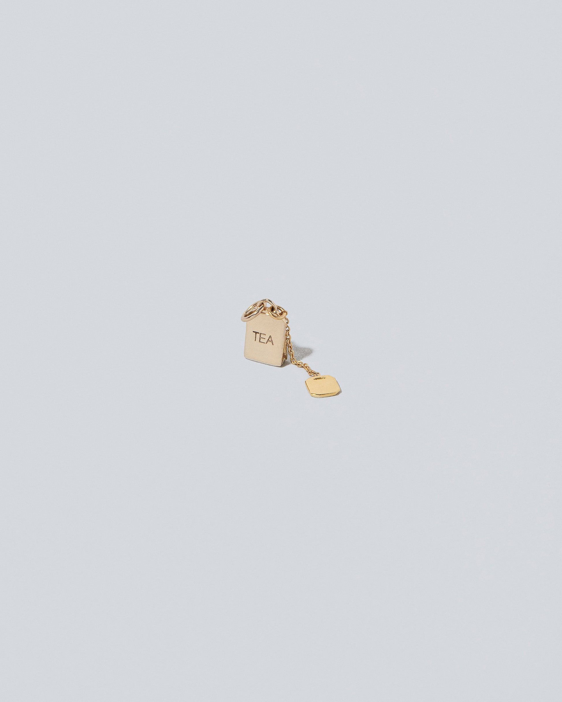 Closeup details of the Tea Bag Charm on light color background.