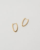 Closeup details of the Gold Solid Tiny Loop Hoop Earrings on light color background.