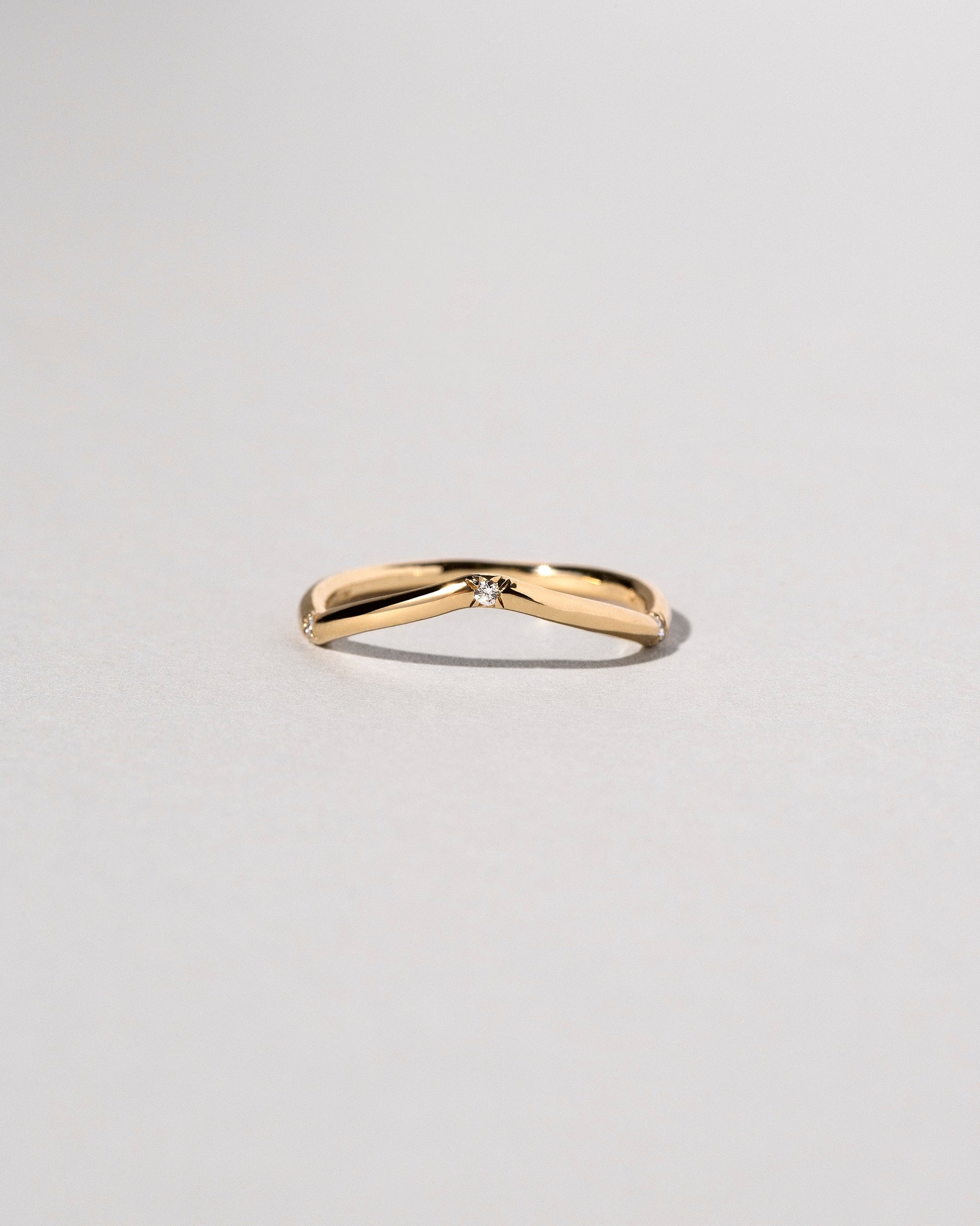 Gold Three Stone White Diamond Low Peak Band on light color background.