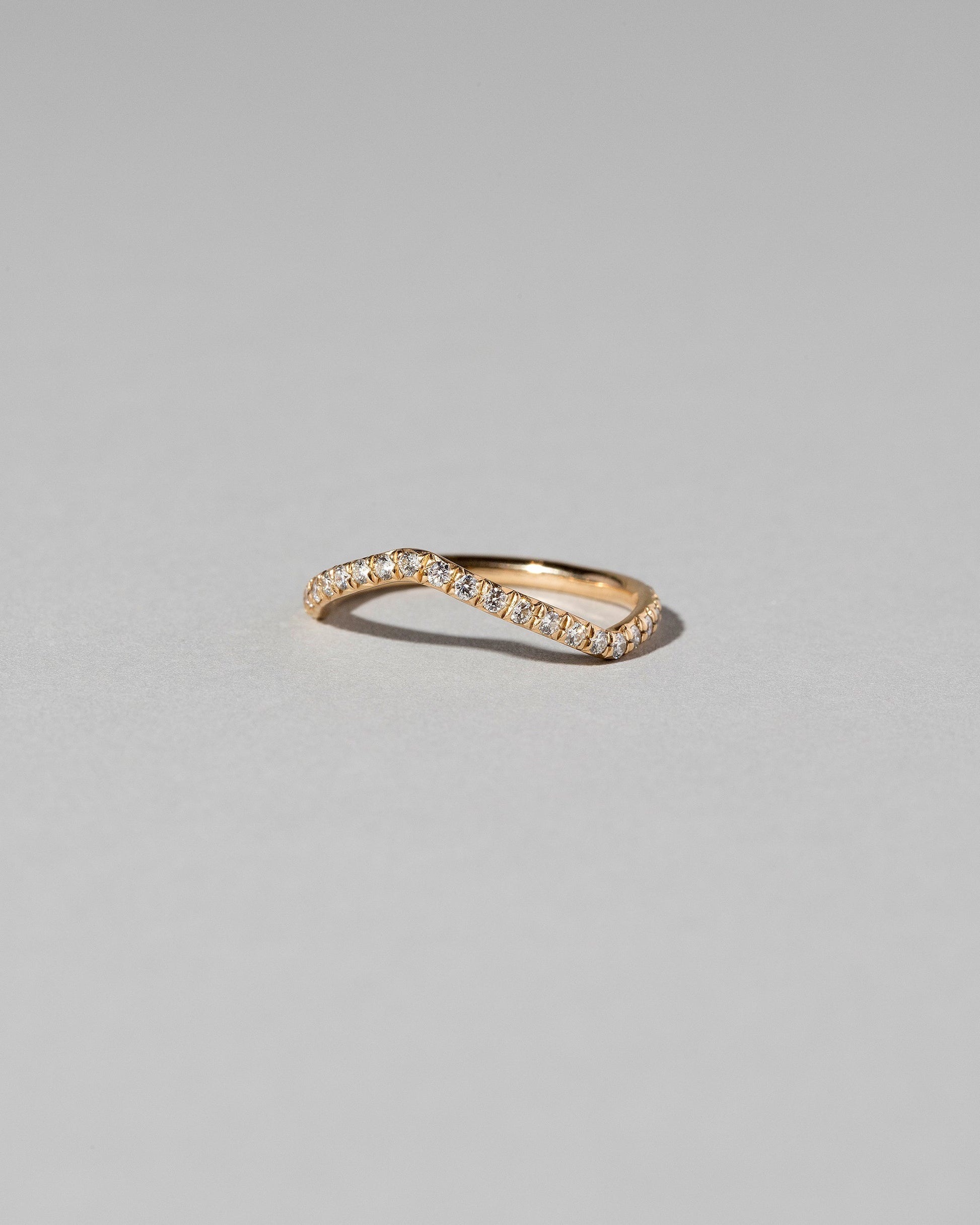 View from the side of the Gold Pavé White Diamond Low Peak Band on light color background.