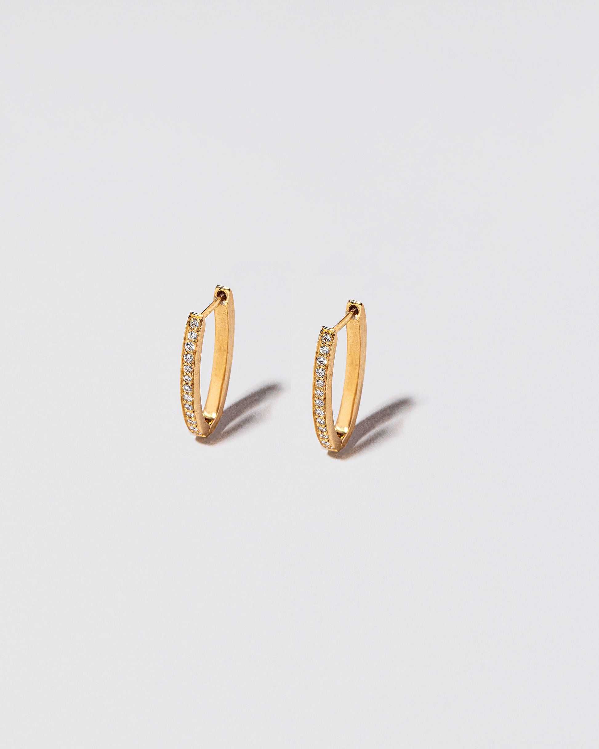 Gold White Diamond Tiny Loop Hoop Earrings on light color background.