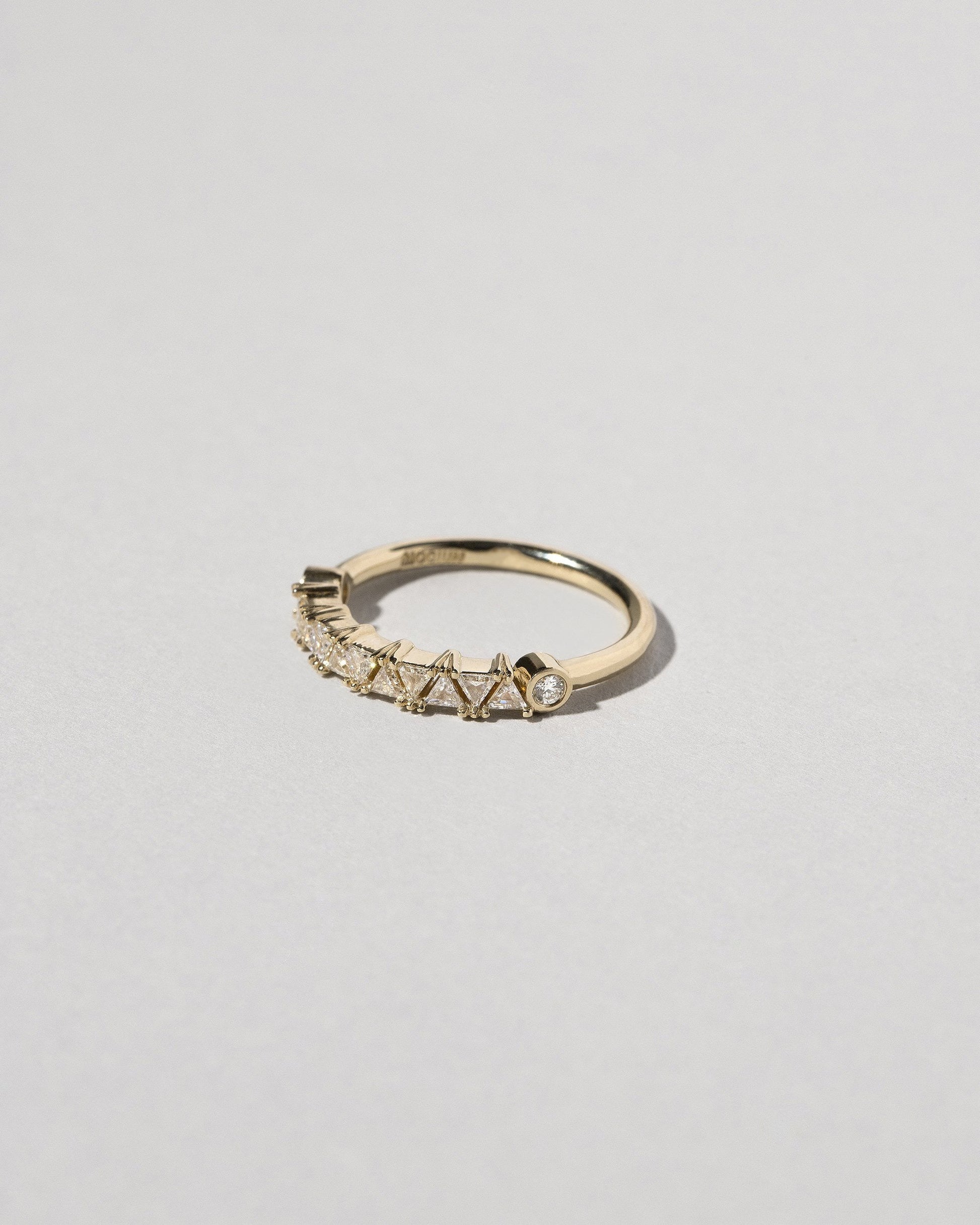 View from the side of the Gold White Diamond Eleven Trillion Ring on light color background.