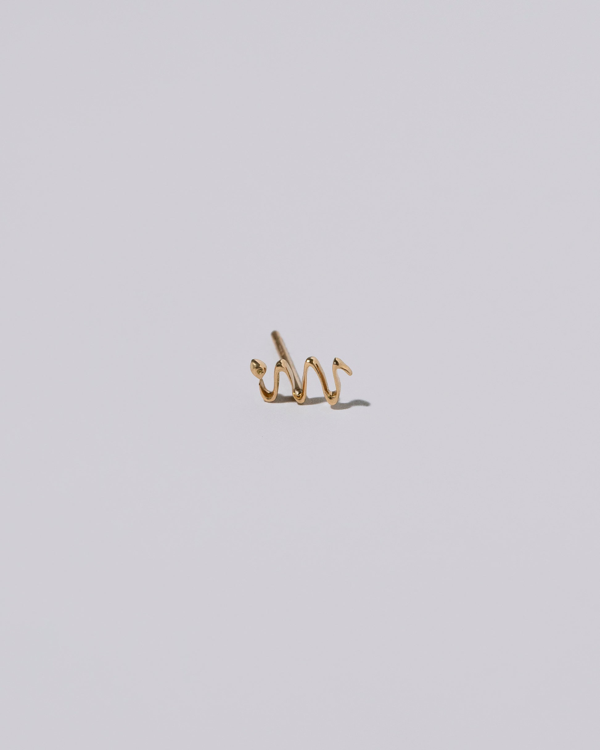 Left Snake Stud Earring Single on light color background.