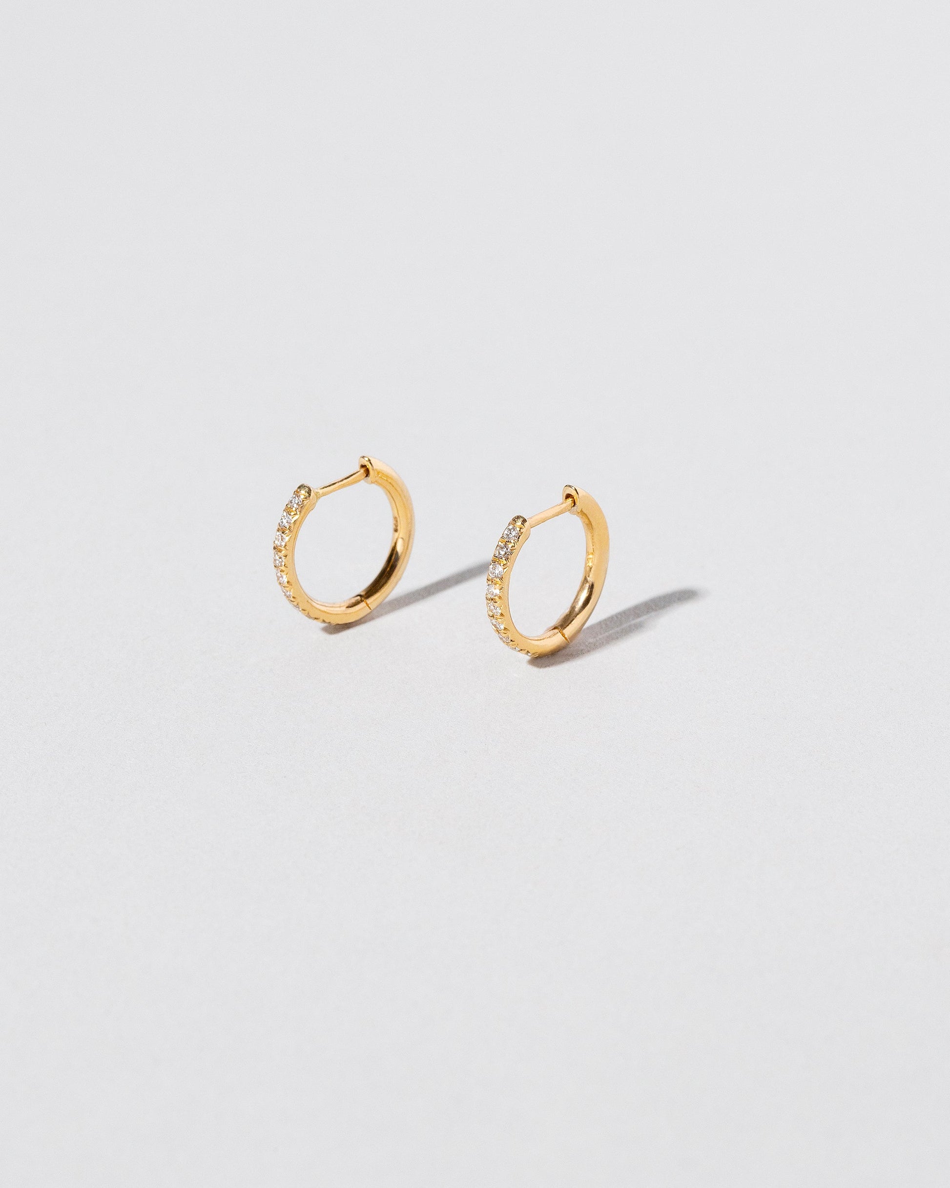 Gold Classic Diamond Snack Hoop Earrings on light color background.