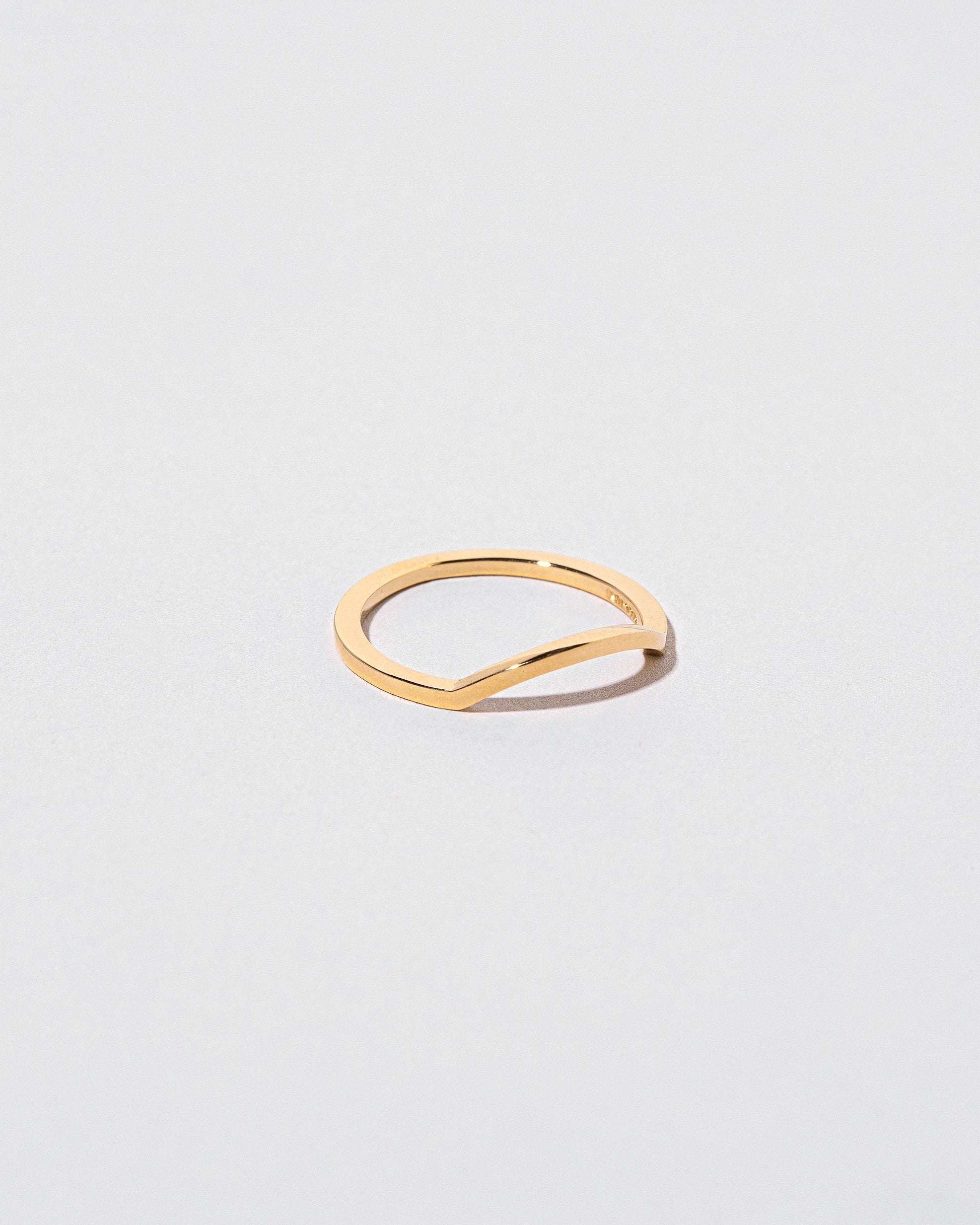 View from the side of the Gold Square Wire Mini Curve Band on light color background.