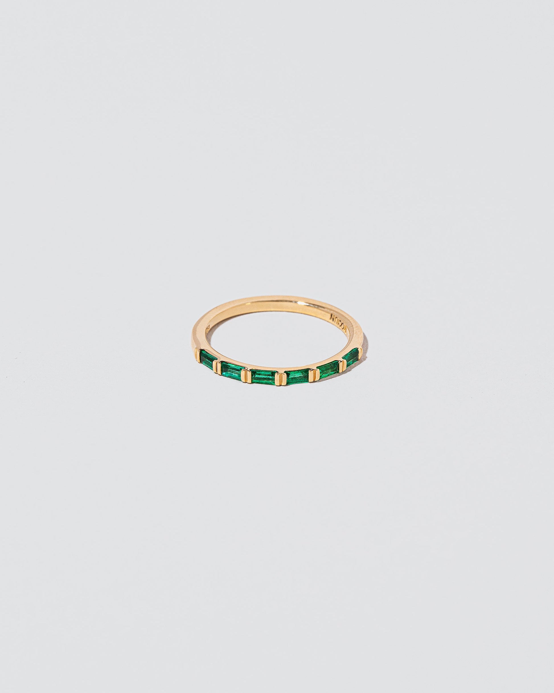 Gold Emerald Bar Baguette Band on light color background.