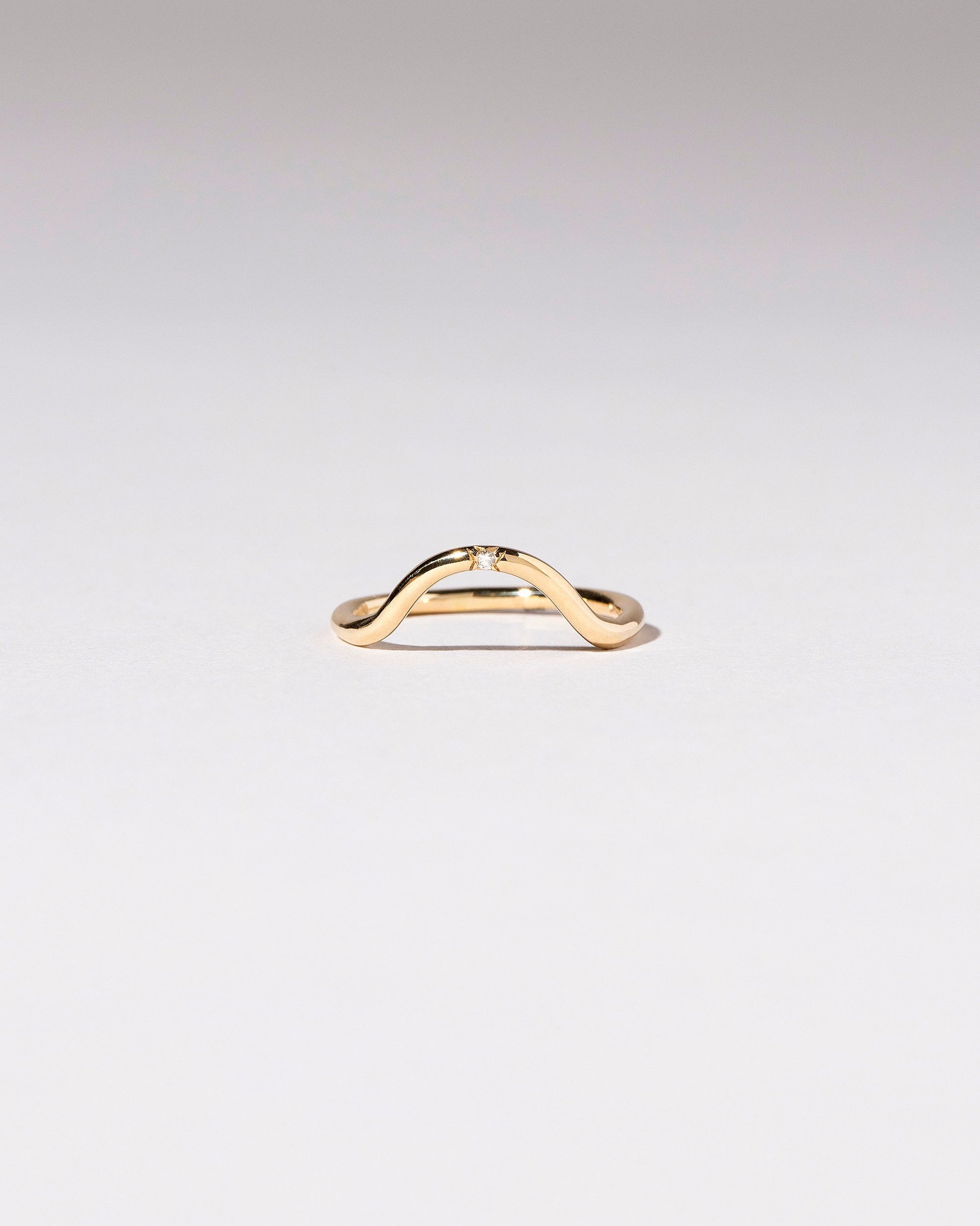 Gold Single Stone White Diamond Curve Band on light color background.