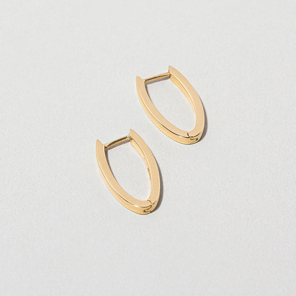 product_details::Closeup details of the Gold Solid Tiny Loop Hoop Earrings on light color background.