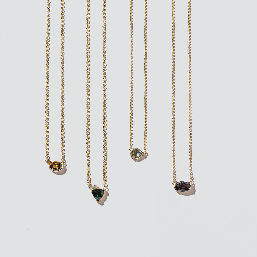 product_details::Group of Geo Cut necklaces on light color background.