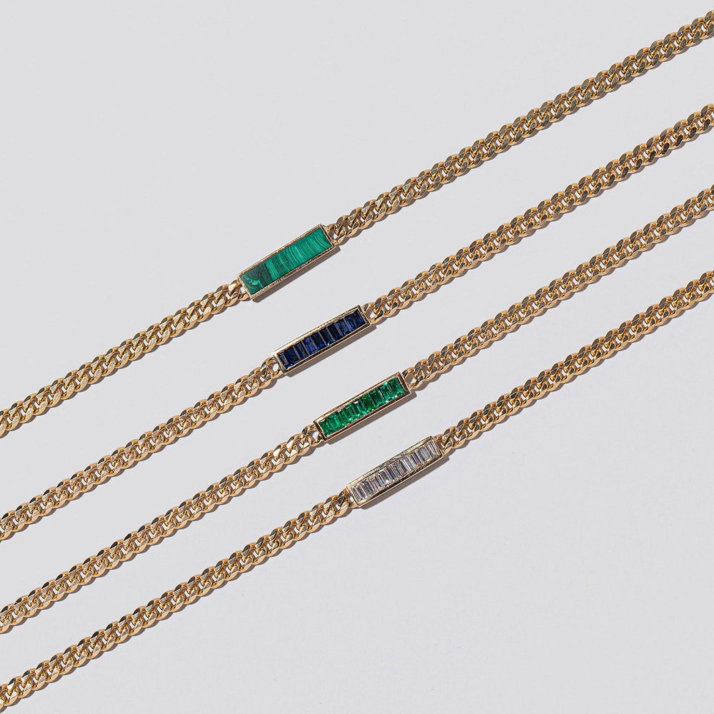 product_details::Group of Identity Chain Necklaces on light colored background.