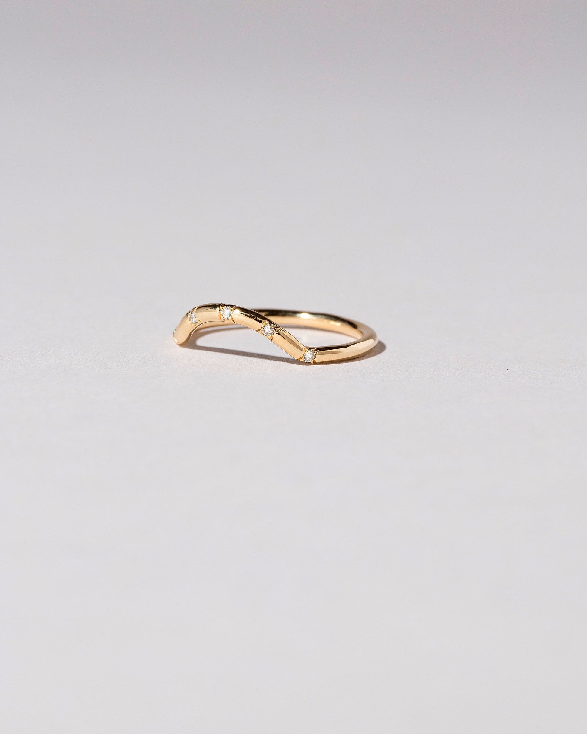 View from the side of the Gold Five Stone White Diamond Mini Curve Band on light color background.
