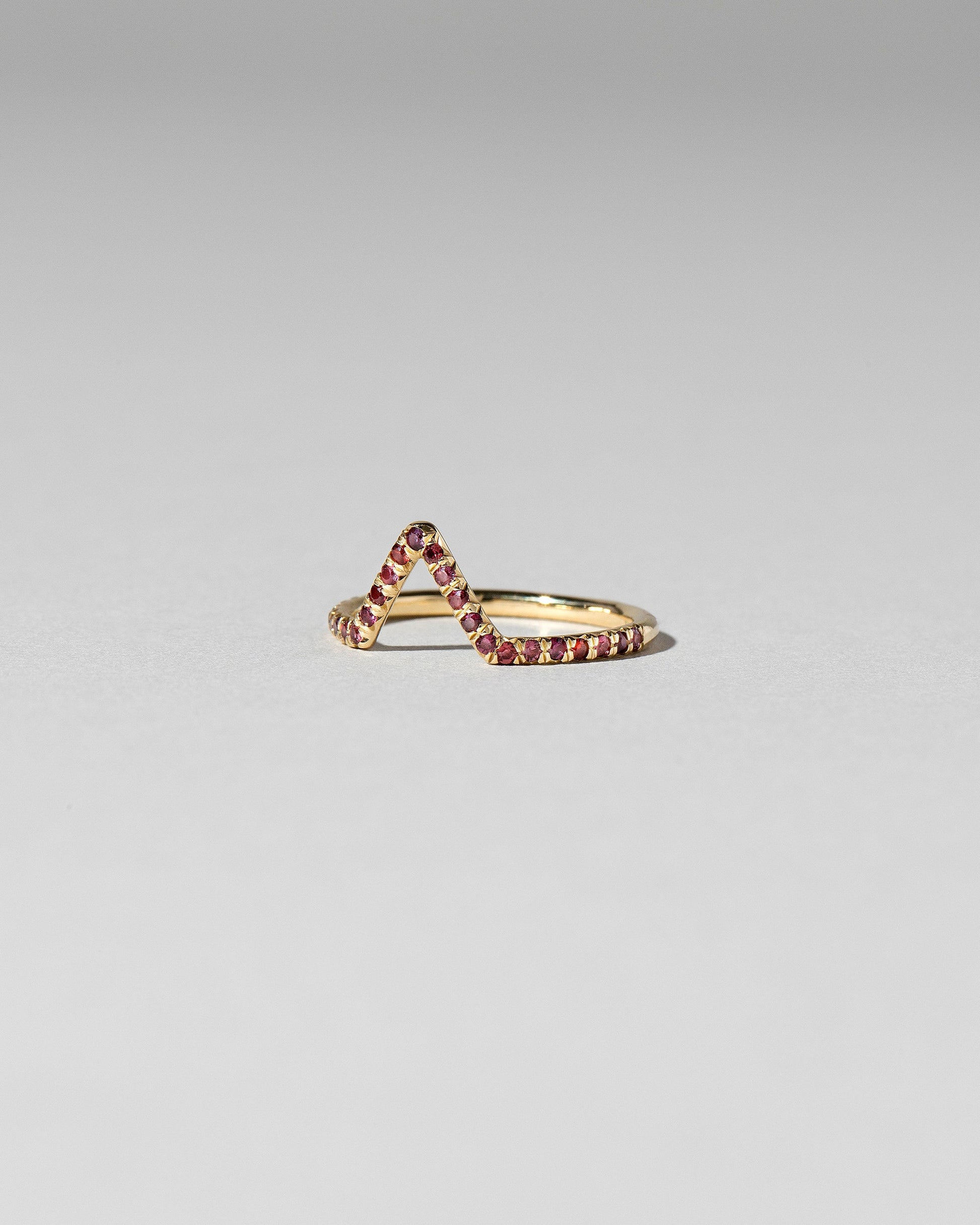 View from the side of the Red Anthill Garnet Pavé Triangle Band on light color background.