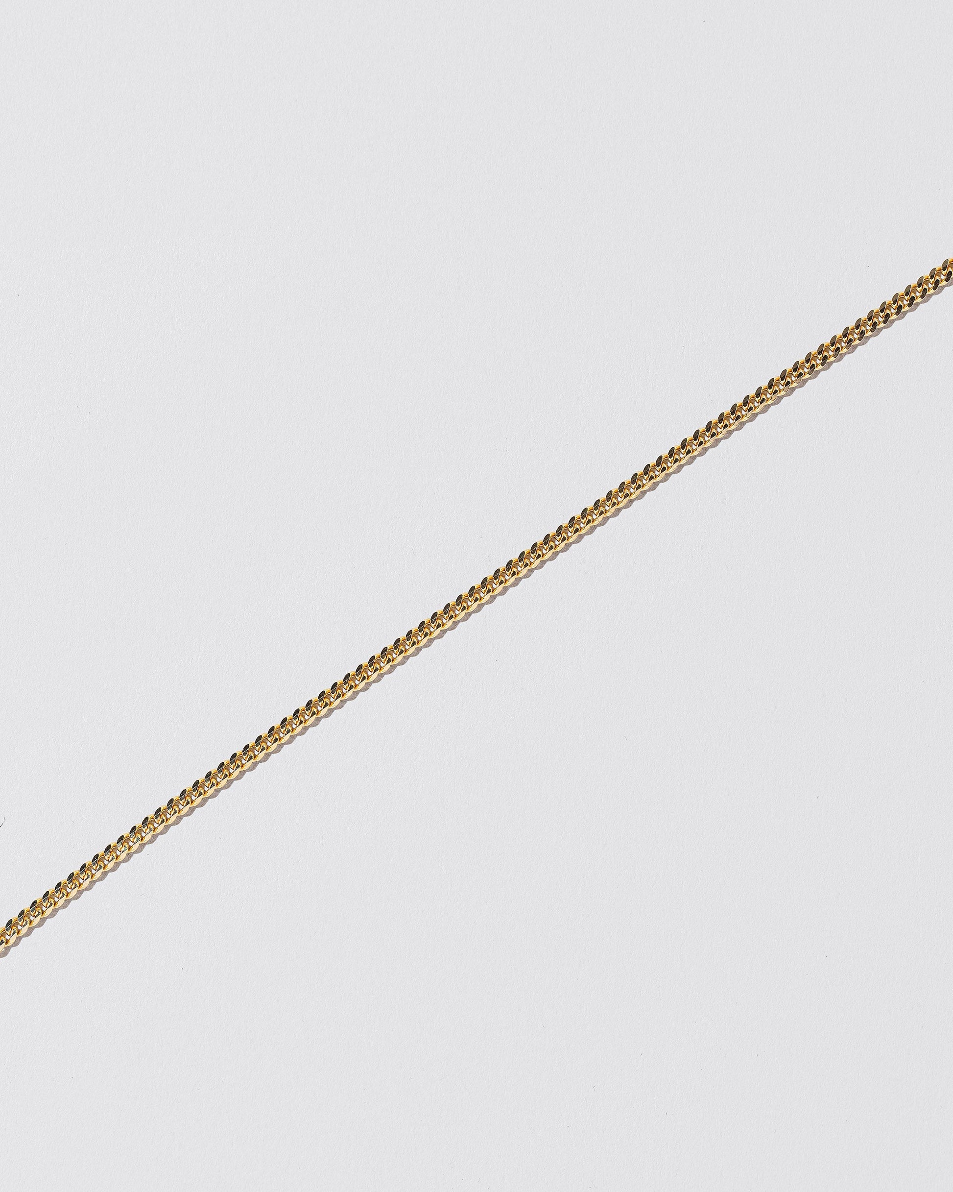 Closeup details of the 2.4mm Curb Chain Bracelet on light color background.