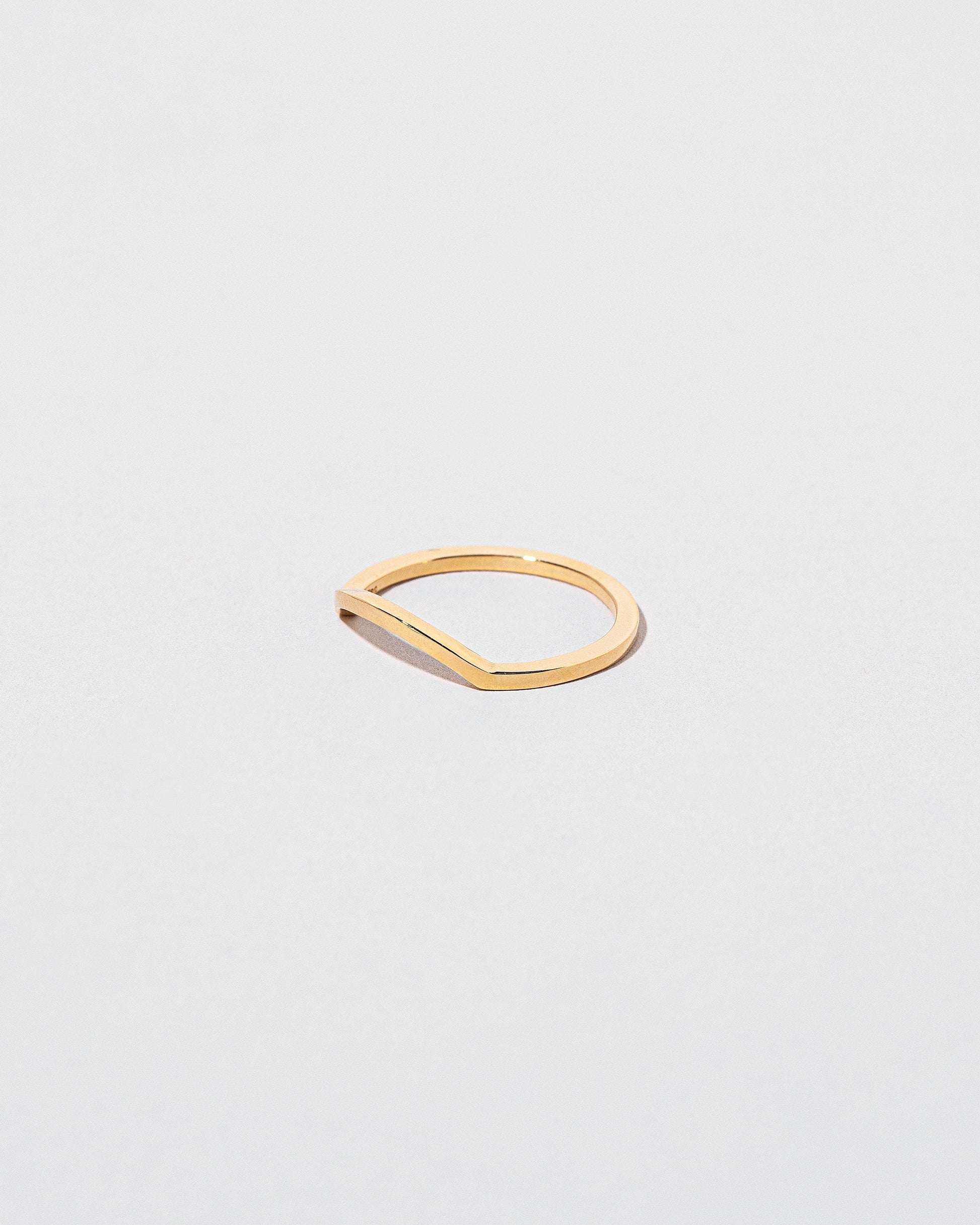 View from the side of the Gold Square Wire Mini Curve Band on light color background.