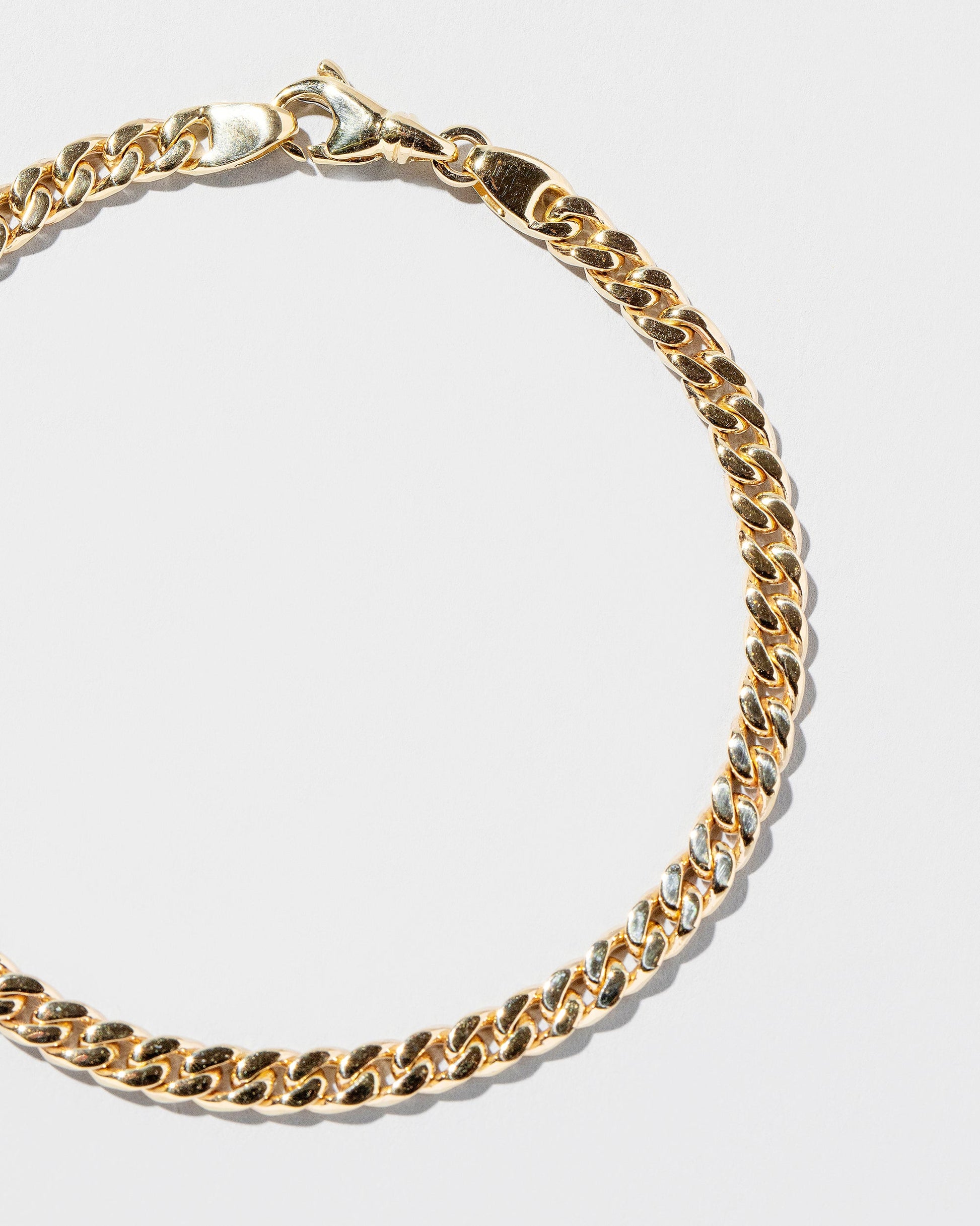 Closeup details of the 4.7mm Curb Chain Bracelet on light color background.
