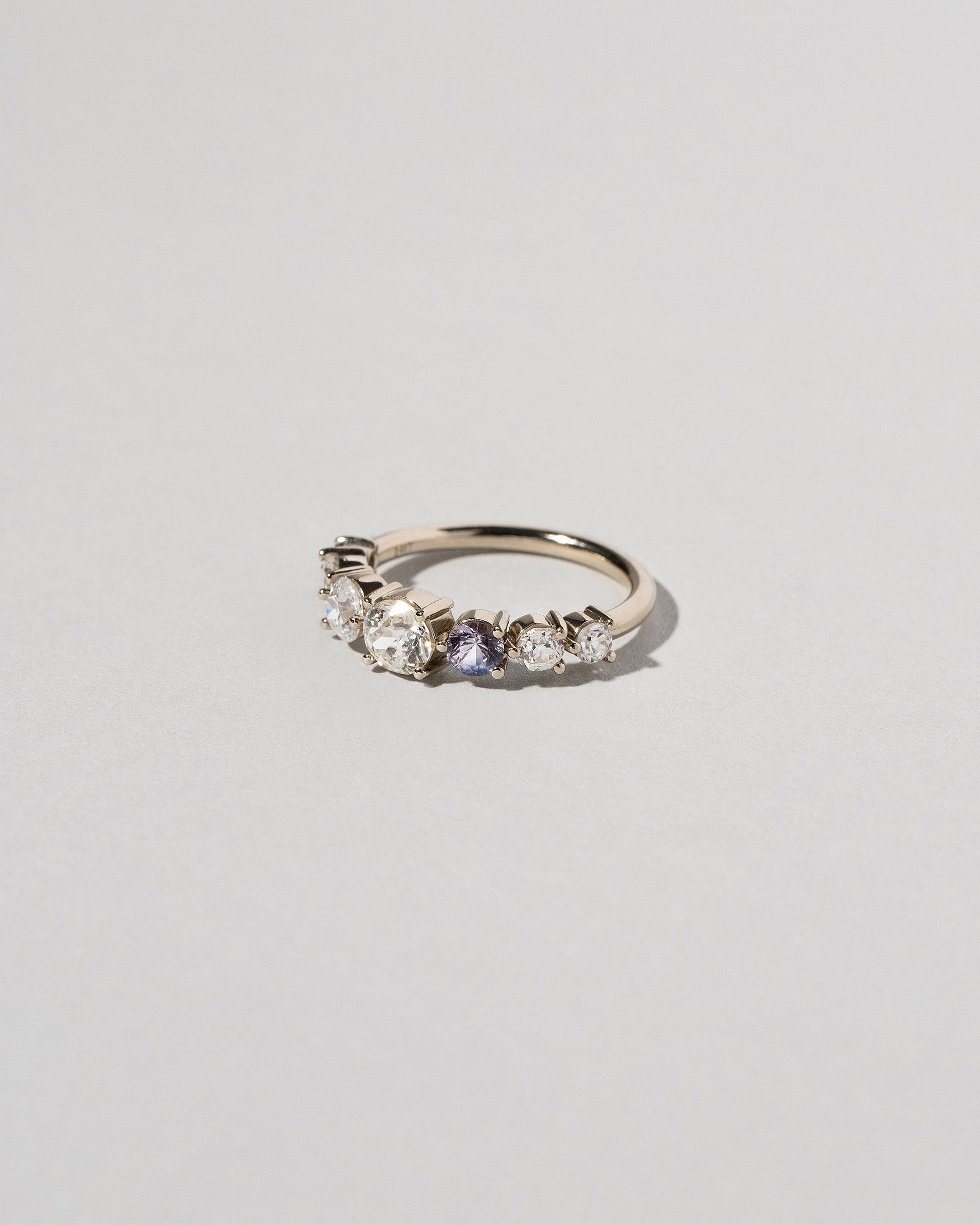 View from the side of the Diamond & Sapphire Line Cluster Ring on light color background.