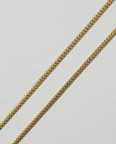 Closeup details of a group of 1mm Ritual Chain Necklaces on light color background.