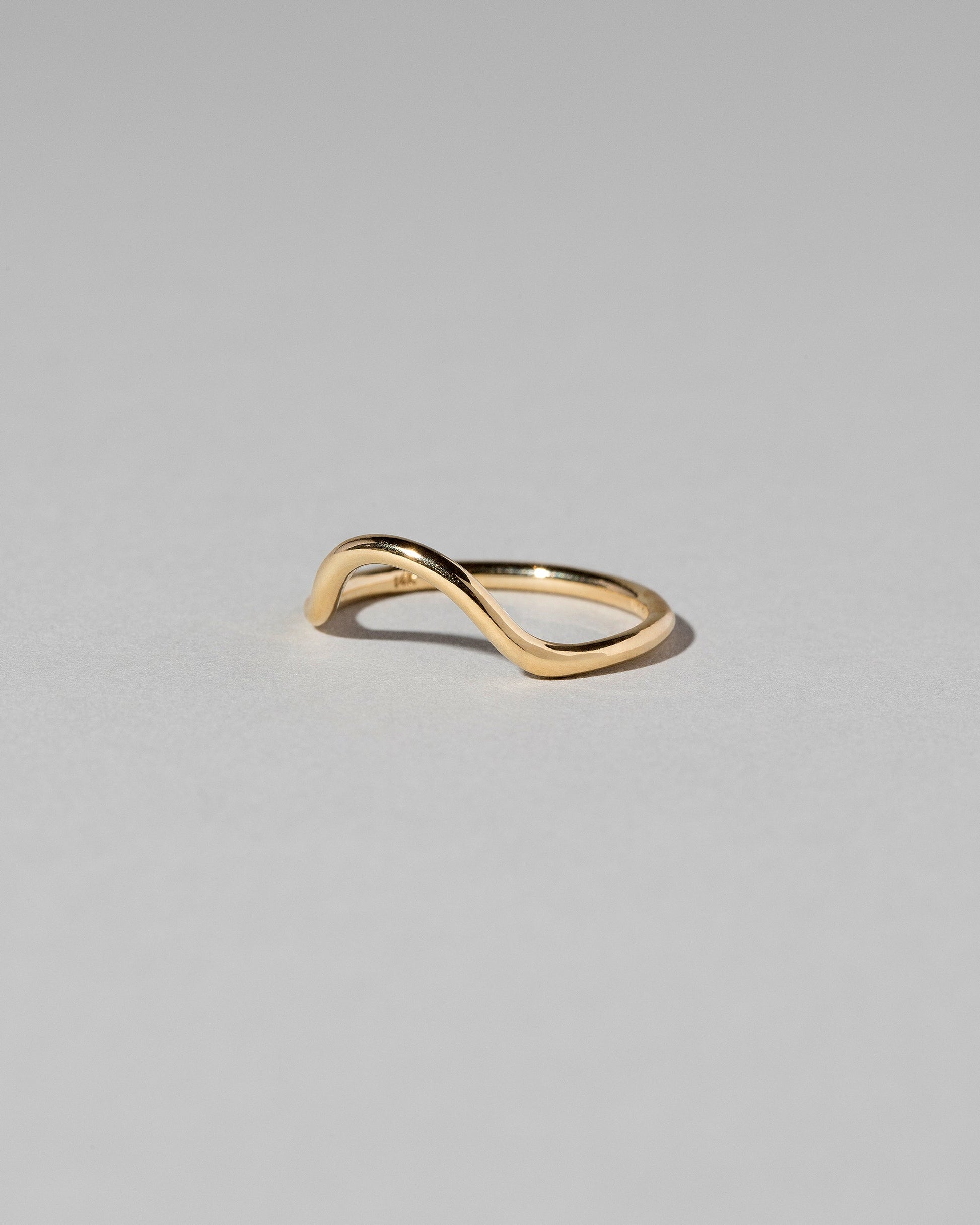 Closeup details of the Gold Solid Round Wire Curve Band on light color background.